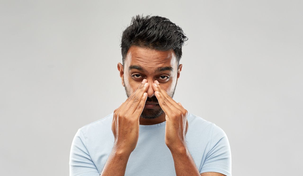 Indian man rubbing his nose