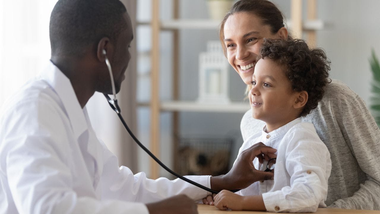 Black pediatrician examining a boy sitting with his mother | Image credit: fizkes - stock.adobe.com