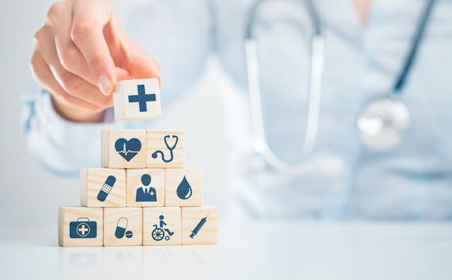 Doctor stacking wood blocks with health care icons | Image credit: REDPIXEL - stock.adobe.com